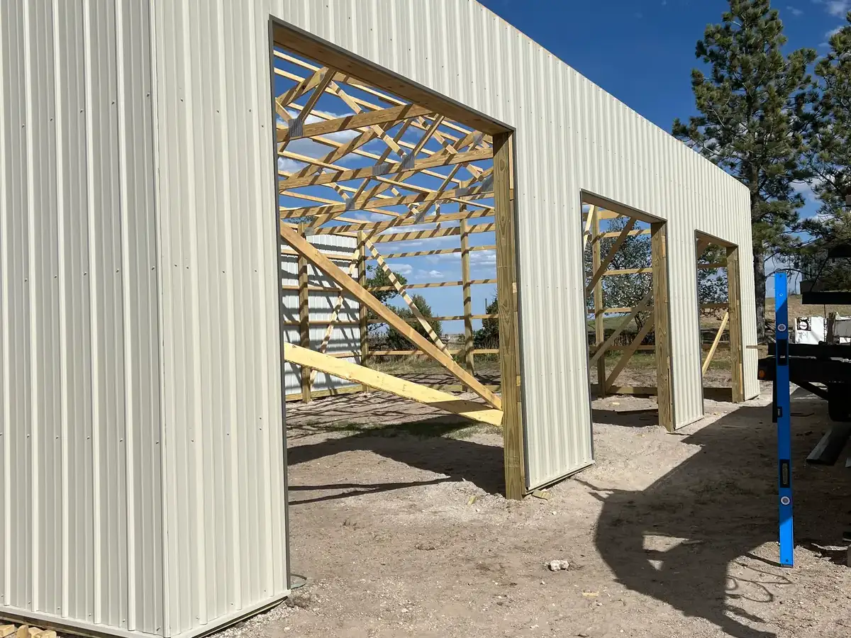 Large framed door openings along a building wall with new light-colored metal siding.