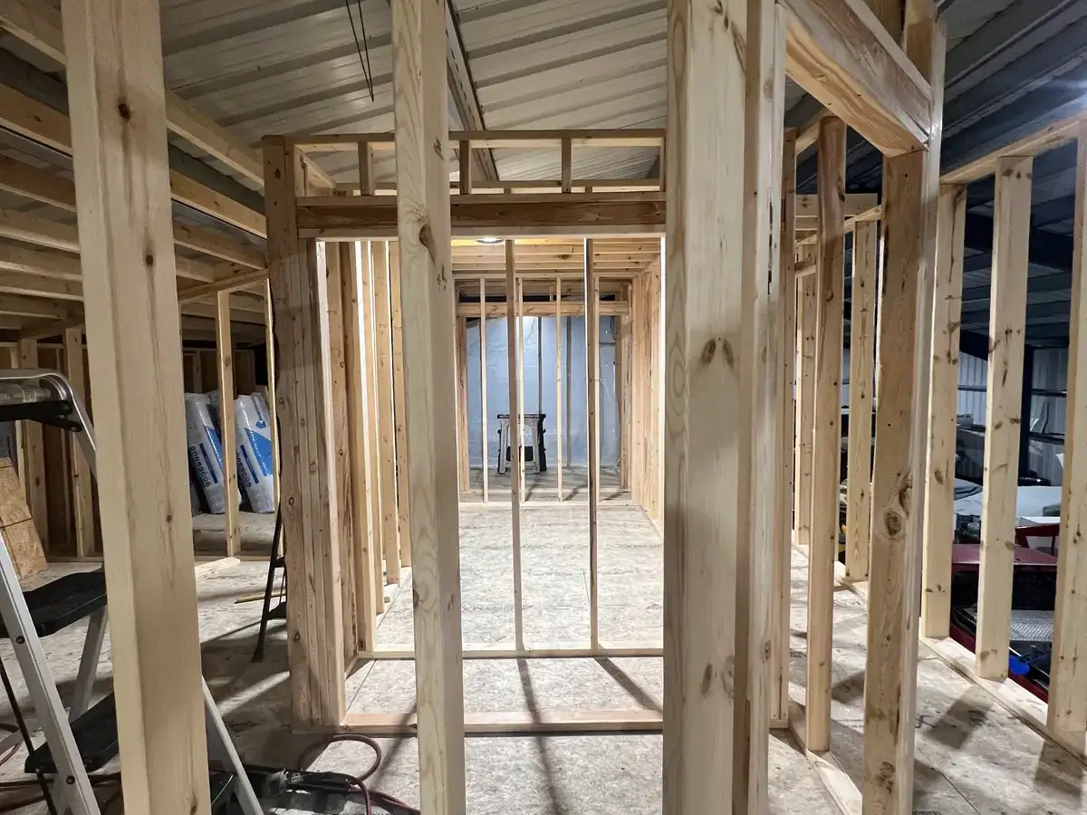 Timber wall studs and door openings inside a metal building during construction.